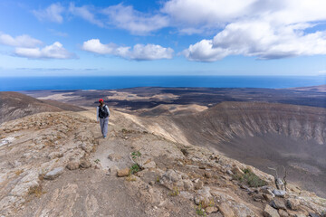 Girl hiking on the edge of the crater of Caldera Blanca, old volcano in Lanzarote, Canary islands, Spain