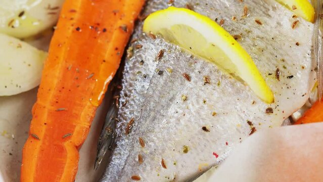 Marinated fresh dorado fish with spices and lemon slices before baking. Top view