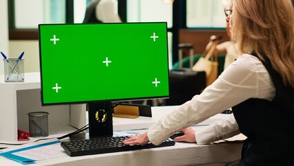 Front desk staff using greenscreen on pc in resort lobby, checking chroma key display with isolated...