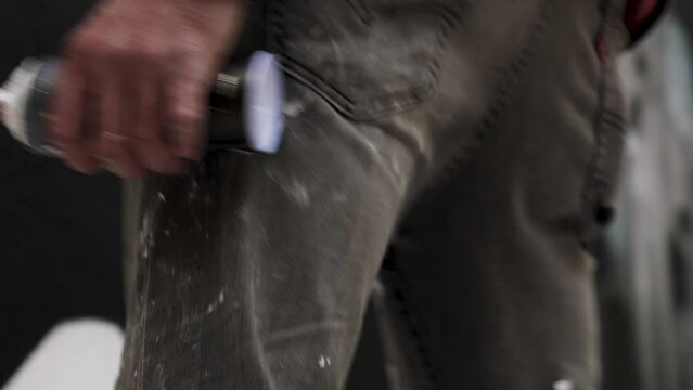 Graffeur tenant une bombe de peinture dans la main, pendant qu'il peint, plan serr&eacute;