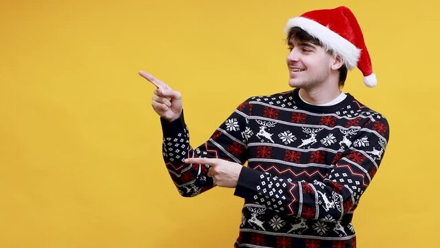 caucasian young man with santa claus hat pointing isolated on background