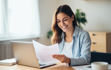 Smiling businesswoman reading financial document and using laptop on desk while working from home