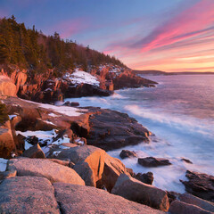 Fototapeta na wymiar A coastal scene during a winter sunrise in Acadia National Park, USA, with the first light painting the rocky shores and the Atlantic Ocean in hues of pink and gold.