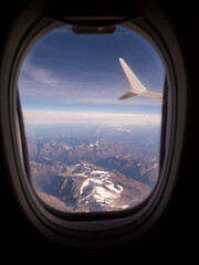 View from an airplane window of a mountain area and left wing, warm sunny day. Travel and tourism...