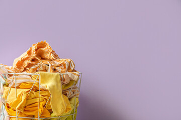 Basket with dirty clothes near lilac wall, closeup