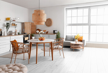 Interior of light kitchen with stylish counters, sofa, table and chairs