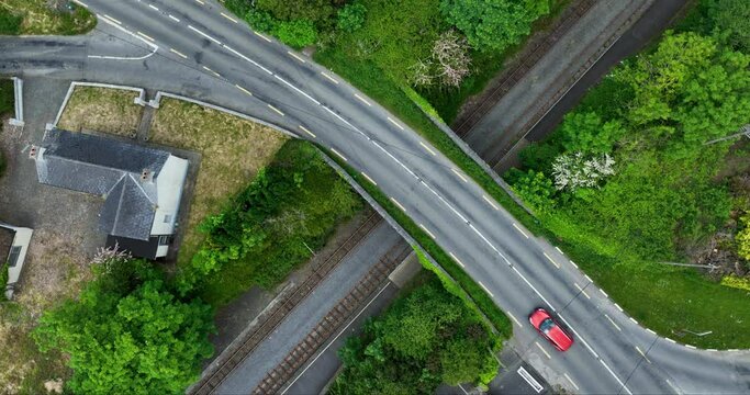 Top shot of a red car driving along a bridge over the railroad tracks 4k
