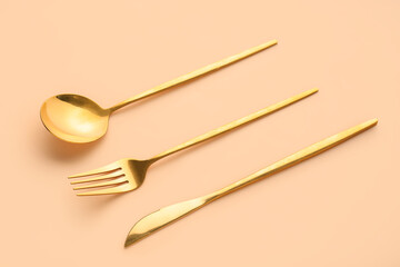 Golden cutlery on beige background