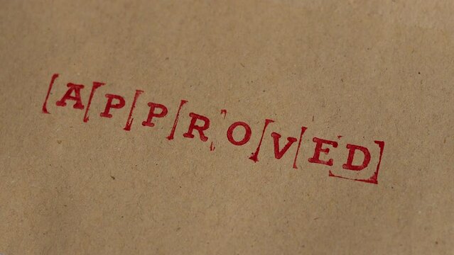 Letter "Approve" are stamped on brown paper. A "d" is stamped at the end completing the word "approved"