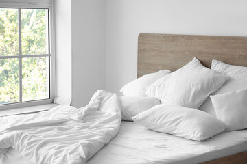 Interior of light bedroom with comfortable double bed and white pillows