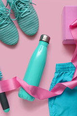 Composition with sports equipment, bottle of water and clothes on pink background