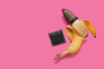 Fresh banana in condom on pink background. Sex education concept