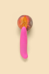 Fresh peach and vibrator on beige background. Sex education concept