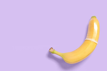 Fresh banana in condom on purple background. Sex education concept