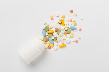 Jar with different medical pills and capsules on color background, top view