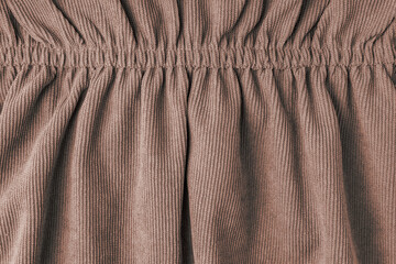 Brown corduroy fabric gathered with elastic close-up. Velveteen texture with folds and drapery....