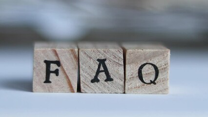 A hand brings the letters FAQ are brought in focus - Powered by Adobe