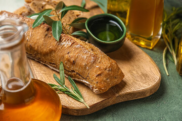 Bowl of fresh olive oil and bread on green background