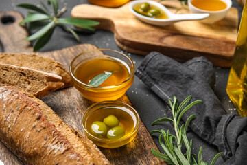 Bowls of fresh olive oil and bread on black background