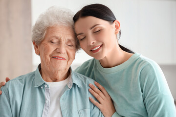 Senior woman with her daughter hugging in kitchen, closeup