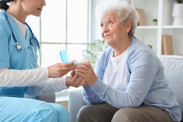 Senior woman with nurse taking pills at home