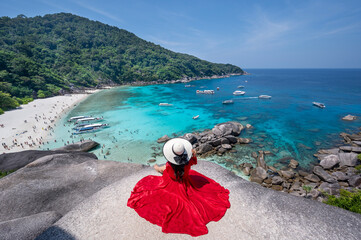 Asian woman in red dress and white sand beach viewing turquoise sea at Similan Island, Thailand