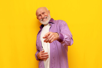 old bald grandfather with gray beard points forward and laughs on yellow isolated background - obrazy, fototapety, plakaty