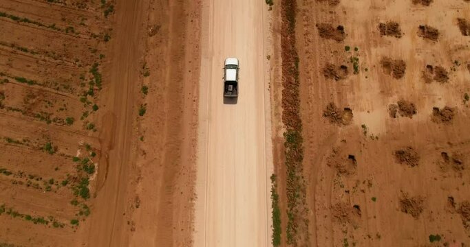Aerial Forward Tilt Up Shot Of Pickup Truck Moving On Dirt Road In Semi Arid Desert On Sunny Day - Mahdia, Tunisia