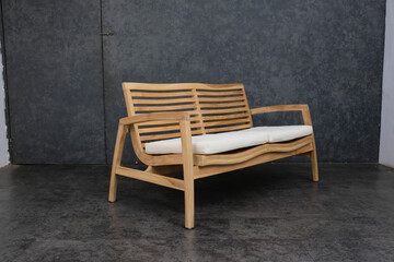 Fototapeta na wymiar a two-seater bench seat made of natural colored teak wood and using white cushions.