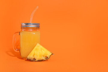 Mason jar of tasty pineapple juice on orange background
