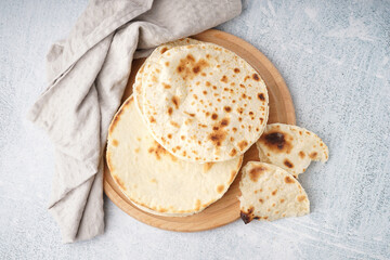 Wooden board of tasty pita bread on white background