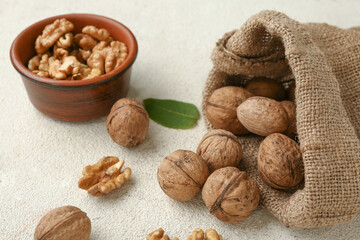 Bowl and bag of tasty walnuts on white background