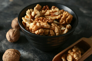 Bowl of tasty walnuts on black background