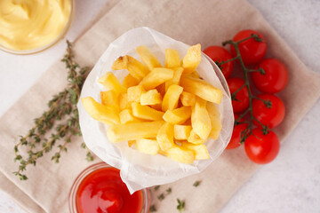 Glass with tasty french fries and sauces on white background