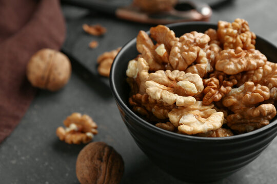 Bowl of tasty walnuts on grey background