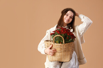 Young woman with chrysanthemum flowers on beige background