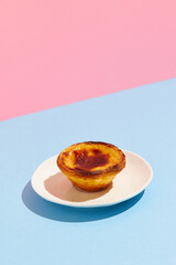 Traditional Portuguese egg tart dessert Pasteis Pastel de nata or Pastels de Belem on the plate over blue and pink background - obrazy, fototapety, plakaty