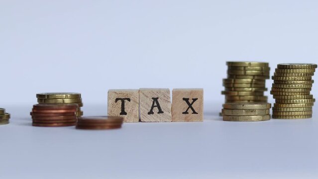 A hand places an X behind the block letters TA forming the word TAX