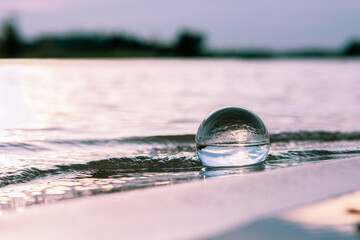 Lensball on the beach shore covered by waves.