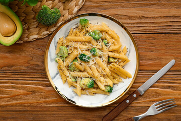 Plate of tasty pasta with broccoli on wooden background
