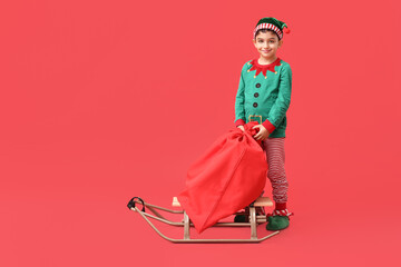 Cute little elf with sled and bag of gifts on red background