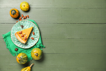 Plate with piece of delicious pumpkin tart and almond on green wooden background