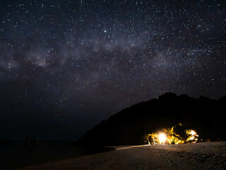 Milky way over beach hut tent by the ocean