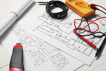 Wiring diagrams, wires and digital multimeter on white table, closeup