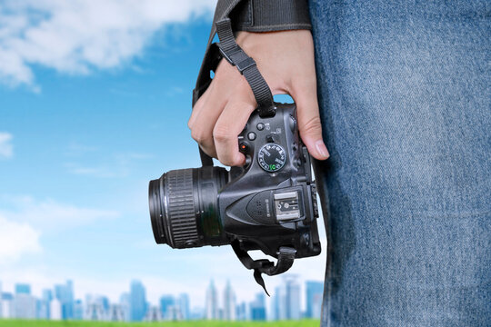 Closeup of a person holding a camera with cityscape background