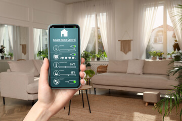 Woman using smart home control system via application on mobile phone indoors, closeup