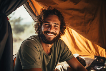 Man sitting inside tent with a smile on his face during camping trip. Created with Generative AI technology - obrazy, fototapety, plakaty