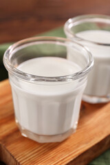 Obraz na płótnie Canvas Glasses of tasty milk on wooden board, closeup