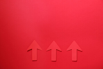 Paper arrows on red background, flat lay. Space for text