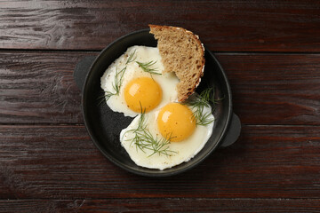 Delicious fried eggs served with bread on wooden table, top view